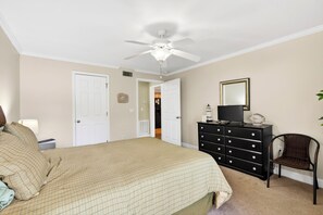 Ein Schlafzimmer mit Bett, Kommode, Stuhl und Deckenventilator.