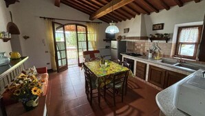 A kitchen with a dining table, chairs, a refrigerator, and a sink. - Sant'Ignazio Farm (Toscana)