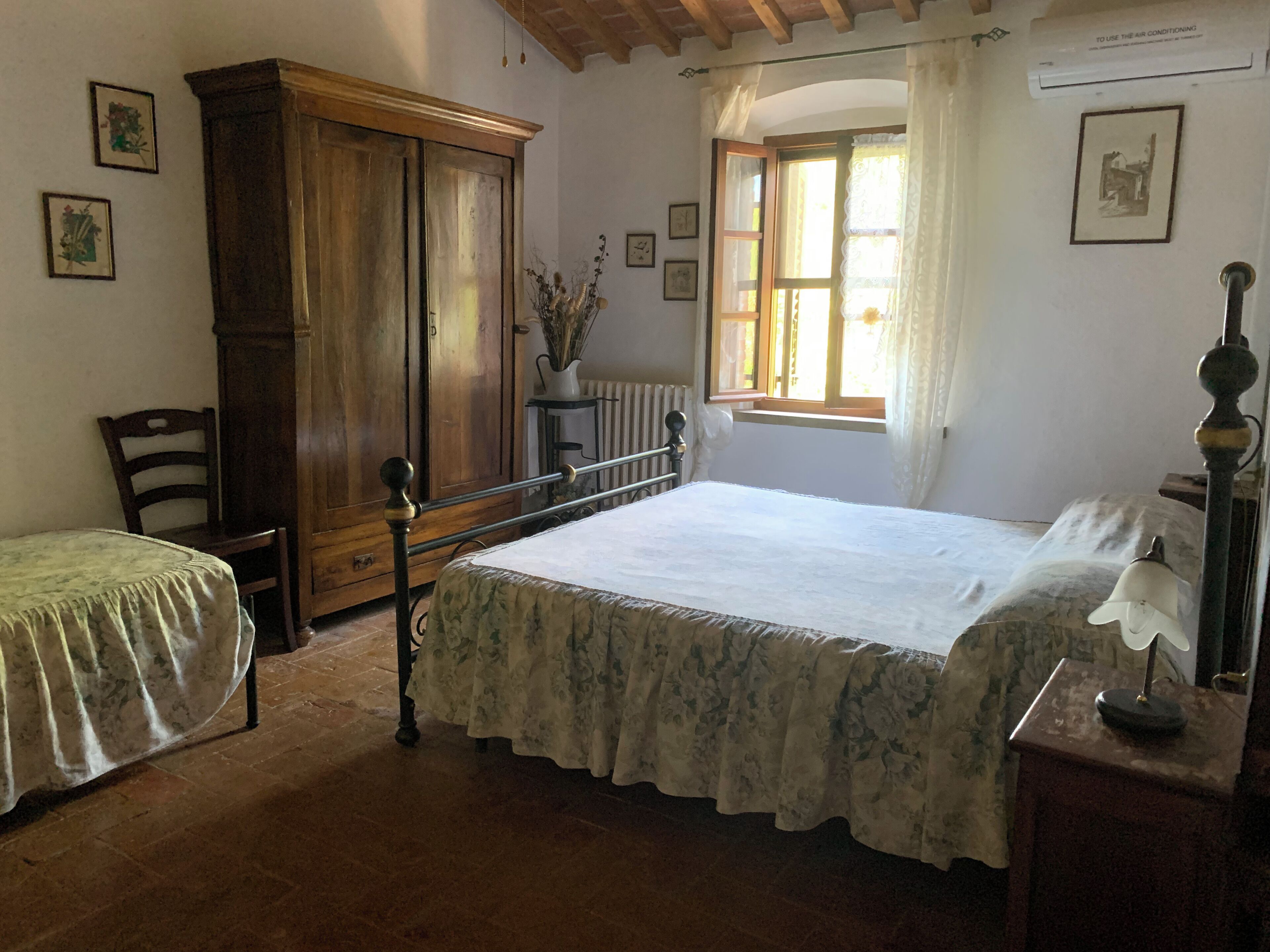 A bedroom with a bed, a chair, a wardrobe, and a window with curtains.