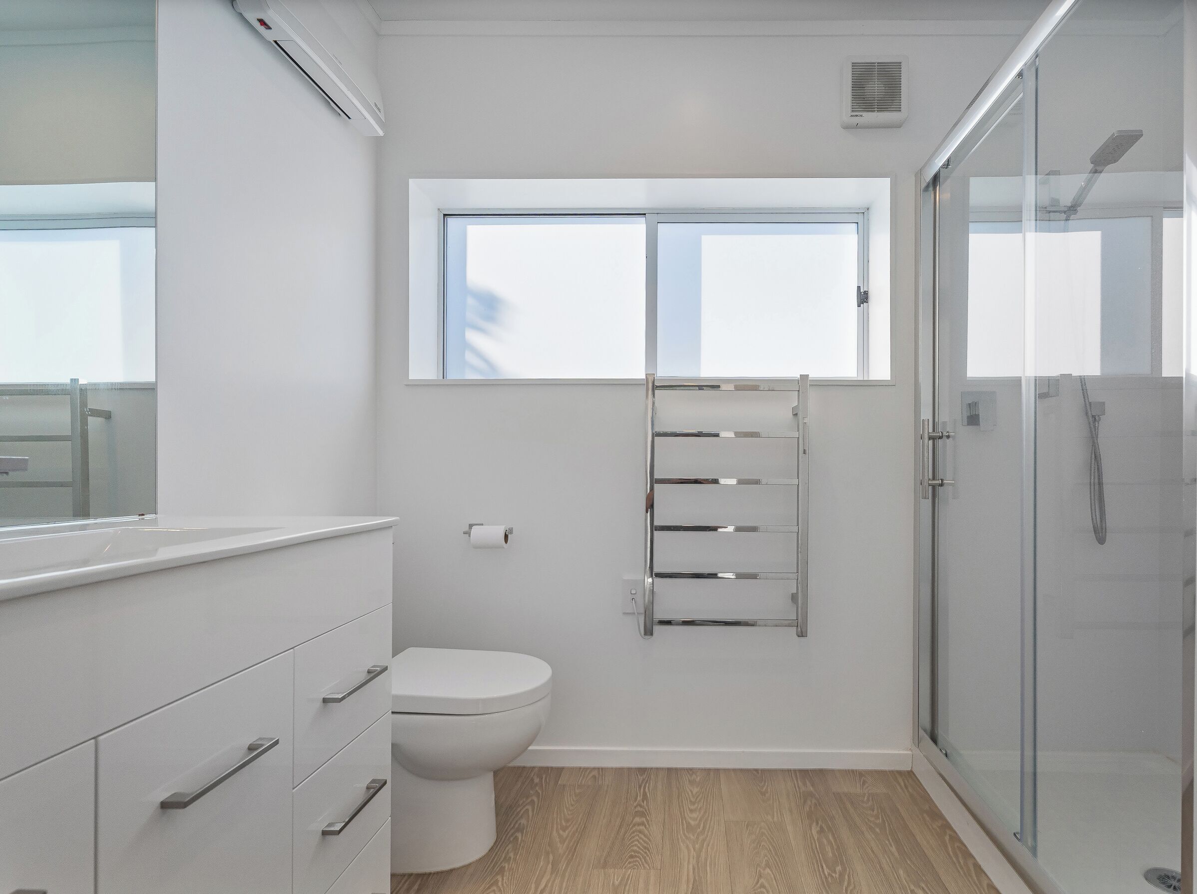 Ein modernes Badezimmer mit Toilette, Handtuchhalter und einer Duschkabine aus Glas.