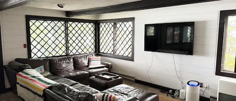 A living room with a sectional sofa, a flat-screen TV, and a large window with a lattice design.