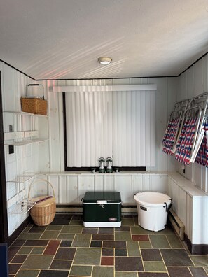 A compact bathroom with a window, a toilet, a green storage box, and a wicker basket.