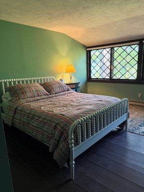 Una camera da letto con un letto, un comodino, una lampada e una finestra.