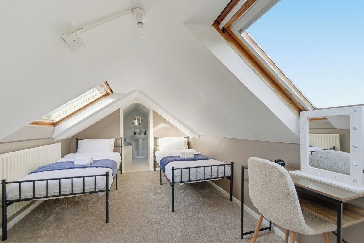 Een slaapkamer met twee bedden, een kaptafel en een spiegel met verlichting.