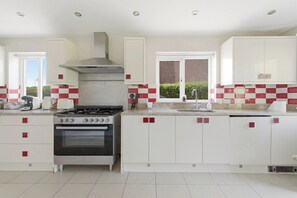 A modern kitchen with white cabinets, a gas stove, and a built-in oven.