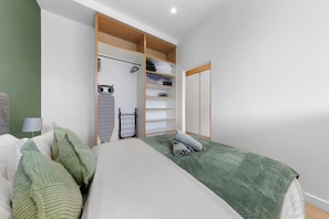 A bedroom with a bed, a wardrobe, and a shelf unit. - Brentford 1 BR Corporate Relocation | Free Parking | Workspace | Gym | AC (Brentford)