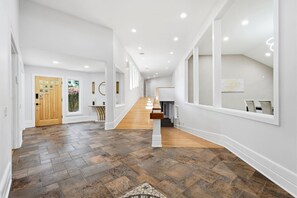 Ein geräumiger Flur mit Holzboden, weißen Wänden und einer Treppe, die zu einer weiteren Etage führt.