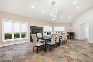 A spacious dining area with a large table and chairs, a fireplace, and large windows. - Spacious ADA 6BR Home for Groups w. Private Pond (Goshen)