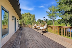 A wooden deck with outdoor seating and a view of a lake. - Spacious ADA 6BR Home for Groups w. Private Pond (Goshen)