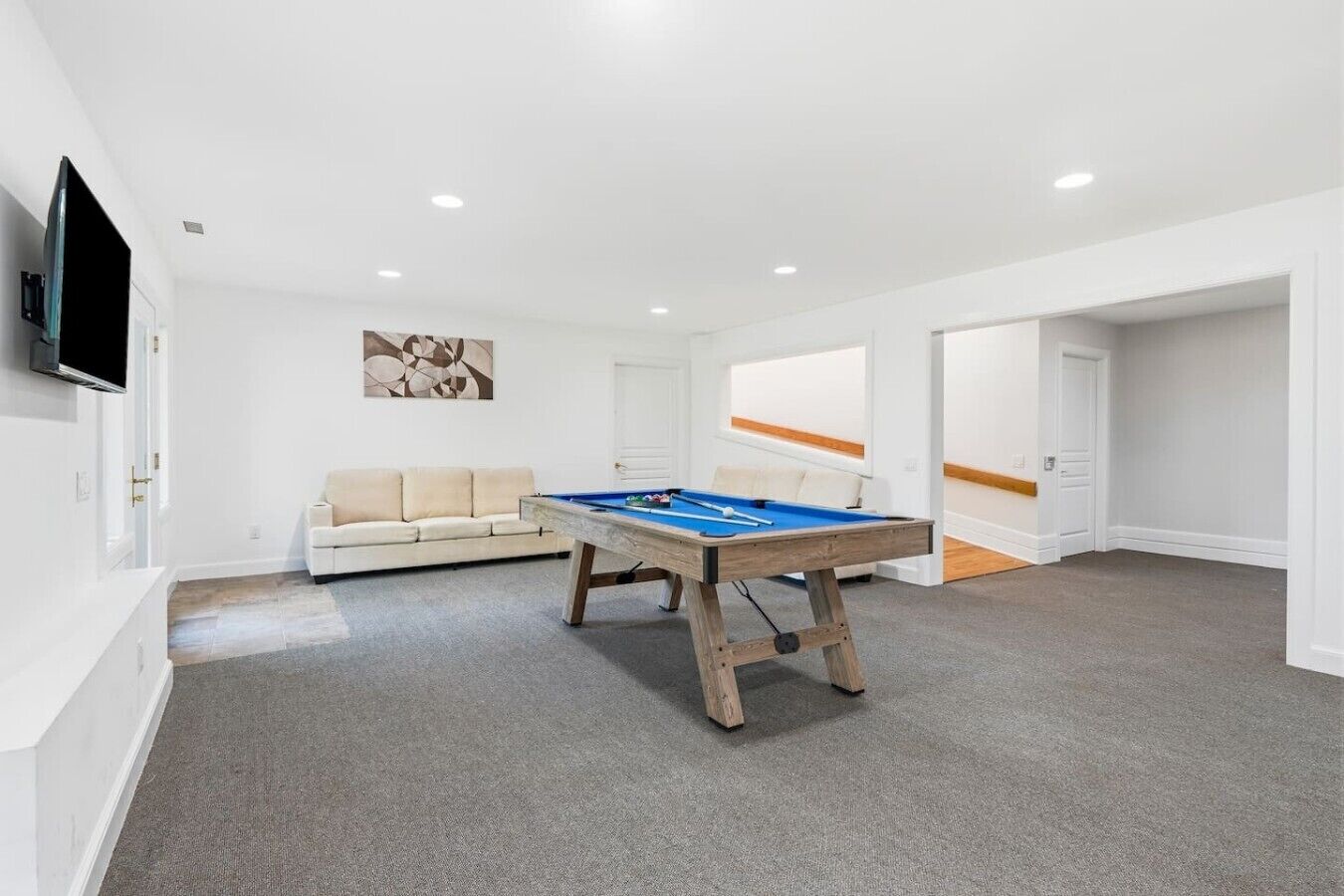Una habitación con mesa de billar, un sofá y una televisión.