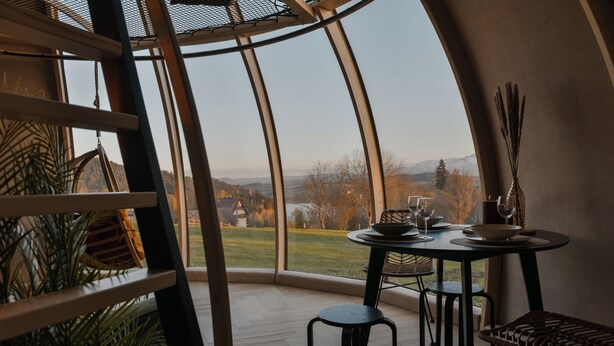 A dining area with a table and chairs, a view of the outdoors, and a large window.