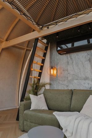 Un interior moderno con un sofá verde, una escalera de madera y una pared de piedra.