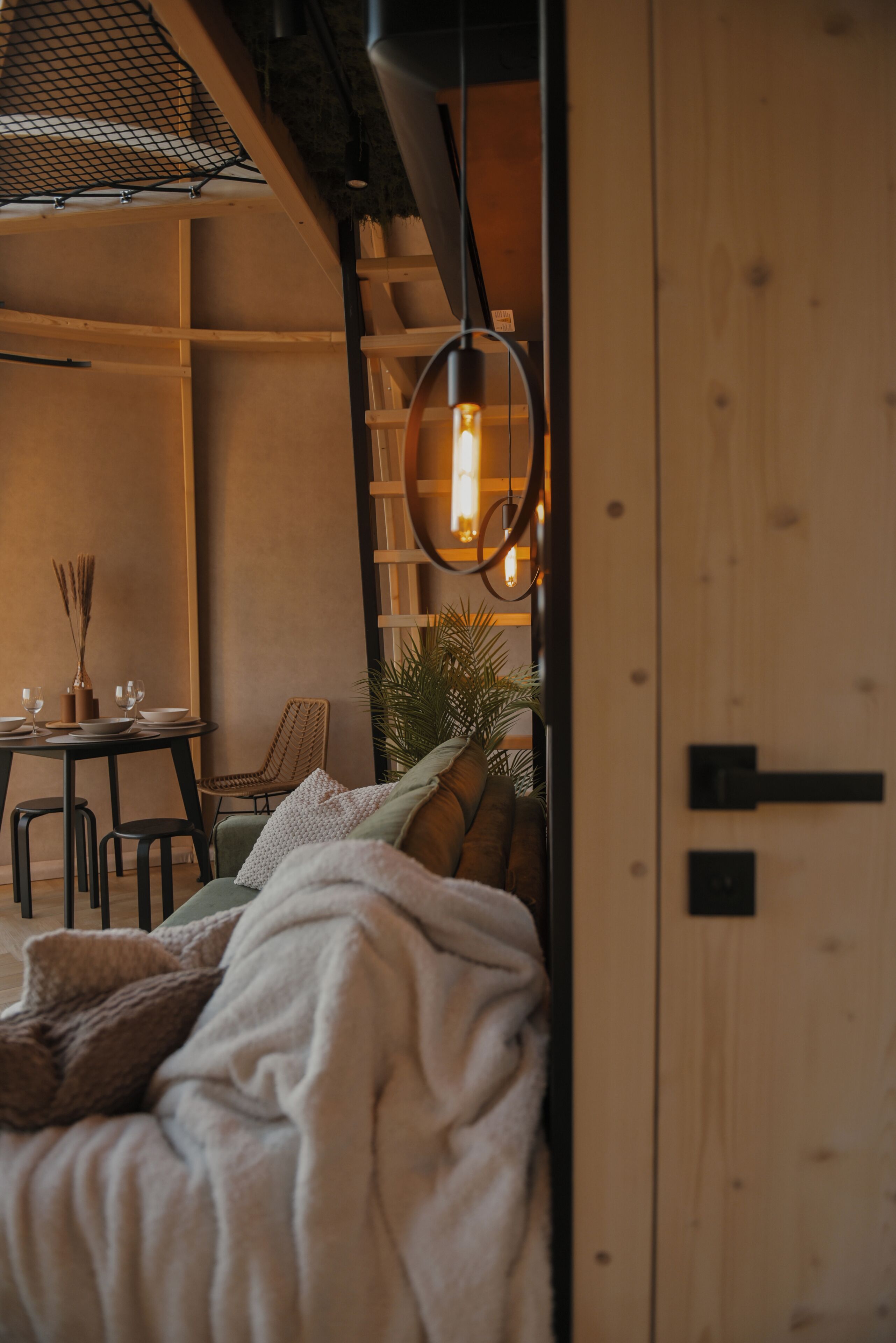 Une pièce confortable avec un lit, une table sur laquelle sont posés des verres et des bols, une chaise et un luminaire suspendu.