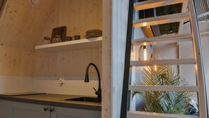 A kitchen with a sink, cabinets, and a shelf with jars.
