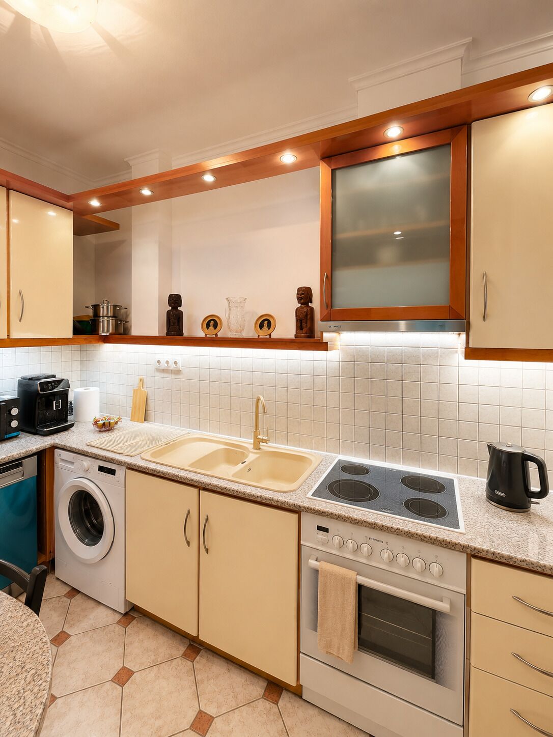 A modern kitchen with a built-in oven, a stovetop, a sink, and a washing machine.