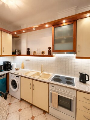 Een moderne keuken met een ingebouwde oven, een kookplaat, een spoelbak en een wasmachine.