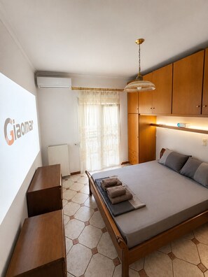Ein modernes Schlafzimmer mit einem Bett, einem Nachttisch aus Holz, einer Wandheizung und einem Fenster mit Vorhängen.