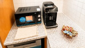 Keittiössä on leivänpaahdin, kahvinkeitin ja astiateline, jossa on pakattuja elintarvikkeita.