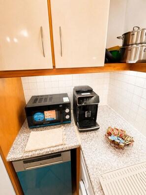 Eine Küche mit Toaster, Kaffeemaschine und Geschirrgestell mit verpackten Lebensmitteln.