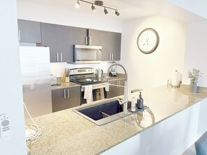 Eine moderne Küche mit Edelstahlgeräten, einem eingebauten Backofen, einer Mikrowelle und einem Spülbecken mit Wasserhahn.