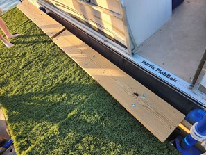 A wooden deck adjacent to a Harris FlotBot, with a grassy area in the foreground.
