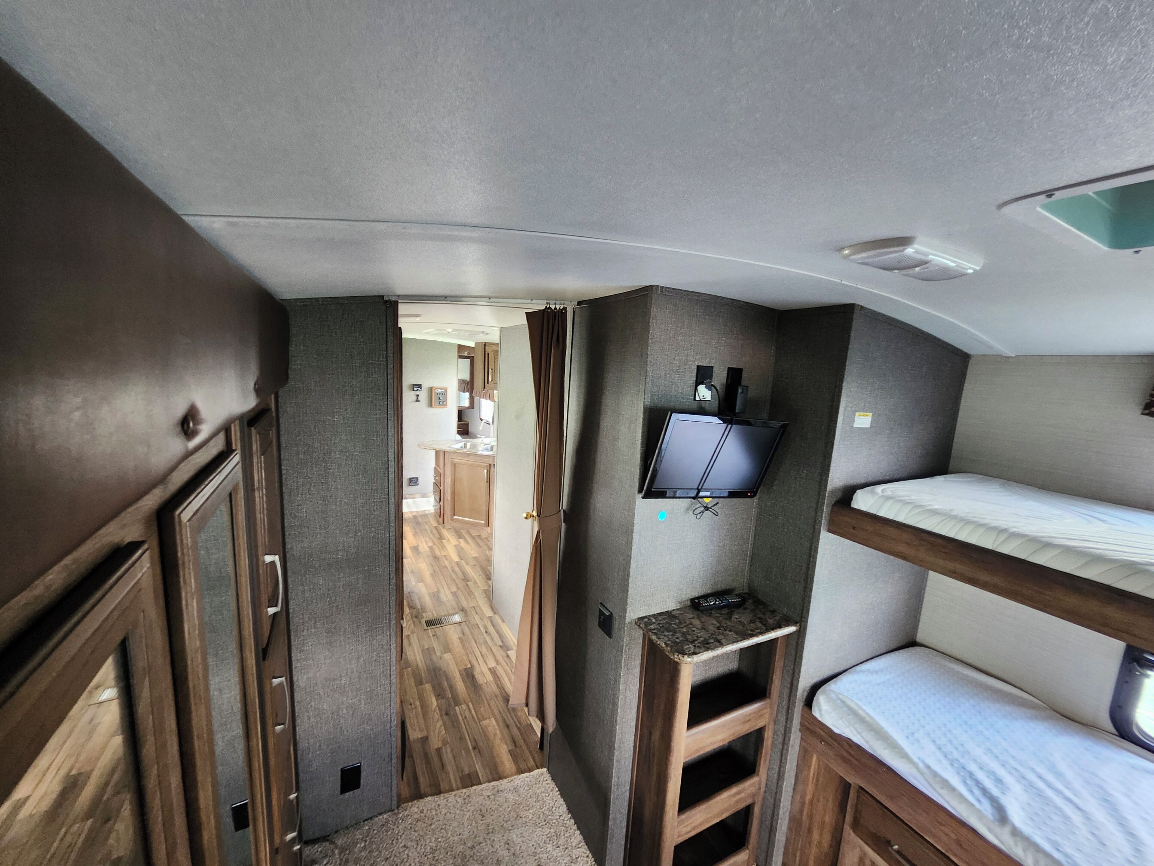 Interni compatti di un camper con angolo cottura, televisore montato e un letto a castello.