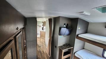 Interni compatti di un camper con angolo cottura, televisore montato e un letto a castello.