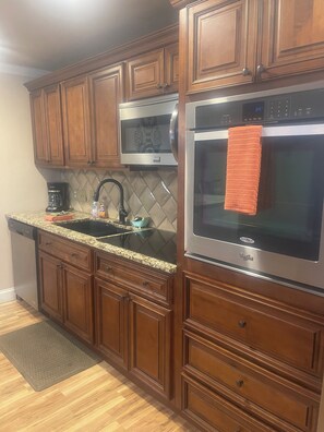 Una cocina con armarios de madera, microondas de acero inoxidable y horno.