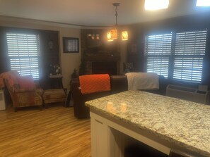A living room with a fireplace, a dining area with a granite countertop, and a seating area with patterned chairs. - JAMBO @ Cades Cove Landing Unit 110 (Townsend)