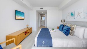 Quarto moderno com cama grande, mesa consola de madeira, televisão e obras de arte nas paredes.