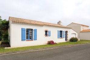 Un bâtiment blanc avec des volets bleus et un toit recouvert de tuiles.