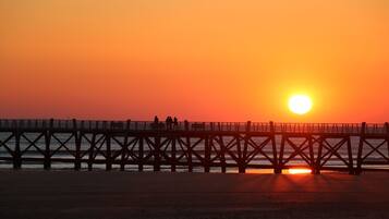 Un muelle que se adentra en el agua con un atardecer de fondo.
