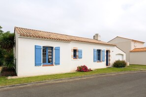 A white building with blue shutters and a tiled roof.