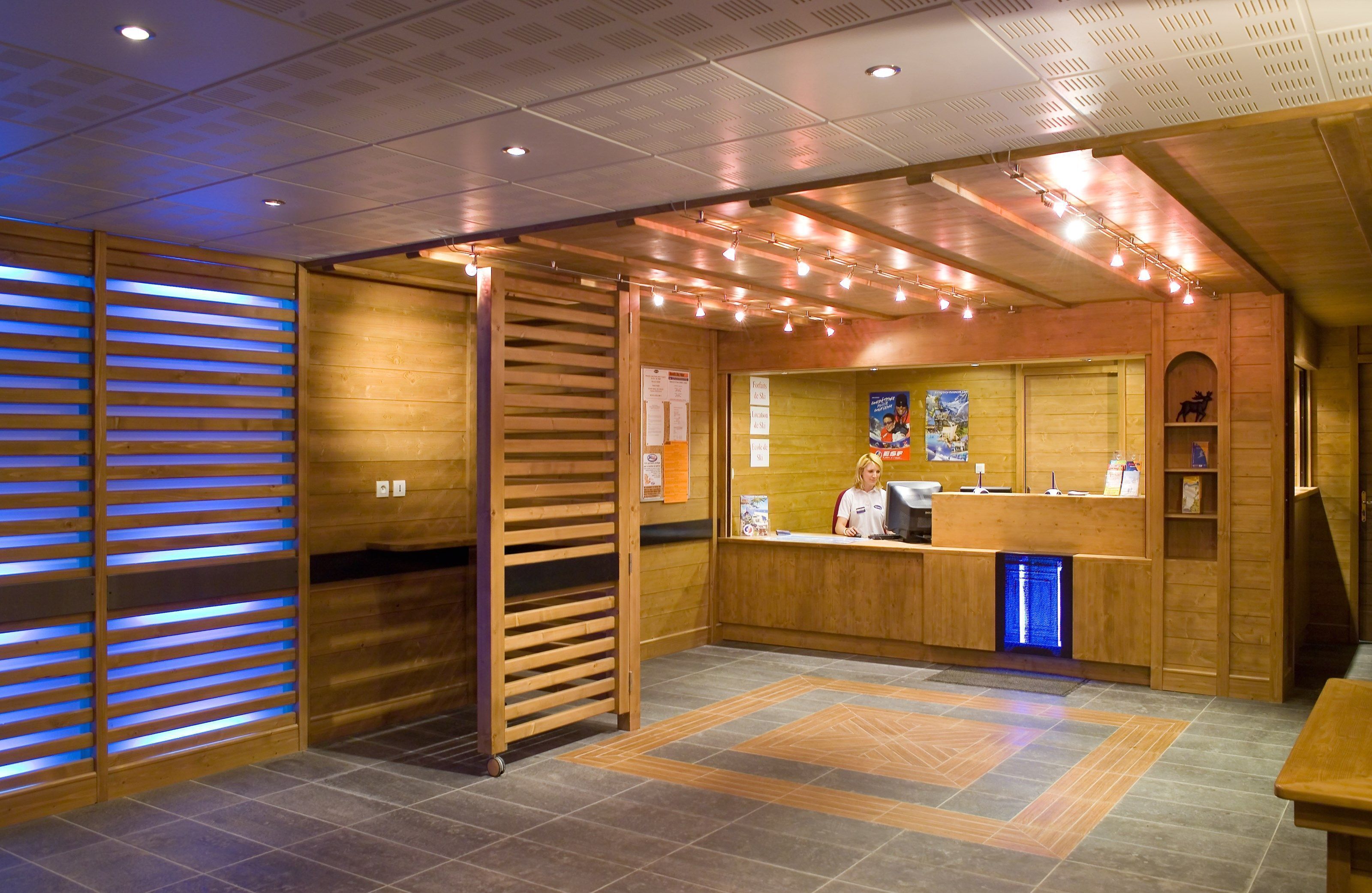 Un espace d’accueil avec un lambris en bois, un comptoir et un lavabo éclairé de lumière bleue.