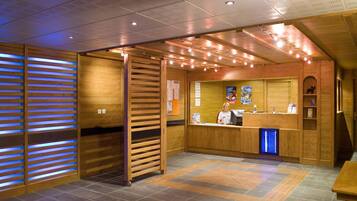 Un espace d’accueil avec un lambris en bois, un comptoir et un lavabo éclairé de lumière bleue.