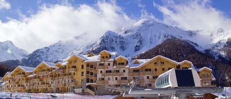 A snow-covered mountain resort with wooden buildings and a ski lift.