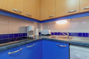 A kitchen with wooden cabinets, a built-in toaster, a coffee maker, and a dishwasher. - Appart au calme coeur de la station, ski aux pieds (Les Orres)