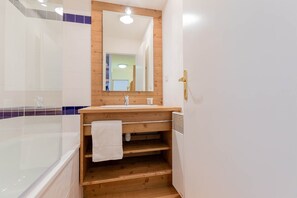 A bathroom with a wooden vanity, a large mirror, a bathtub, and a towel rack. - Départ et retour ski aux pieds !  Appartement 7p (Les Orres)