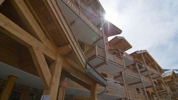 Un chalet in legno con diversi balconi e facciata in pietra.