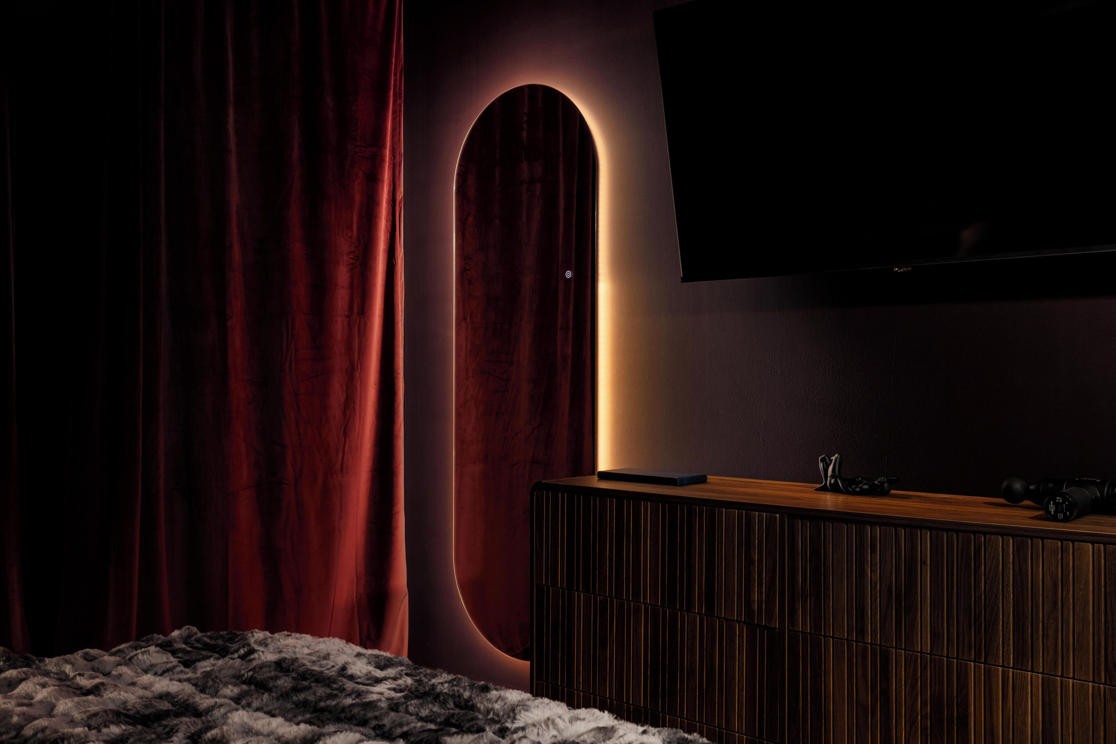 Une pièce sombre avec un grand téléviseur à écran plat fixé au mur, un meuble en bois et un espace recouvert de fourrure.