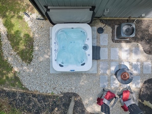 Un jacuzzi con revestimiento de piedra, un ventilador y zona de estar con cojines.