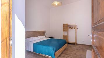 Ein Schlafzimmer mit Bett, Nachttisch, Pendelleuchte und Holzschrank.
