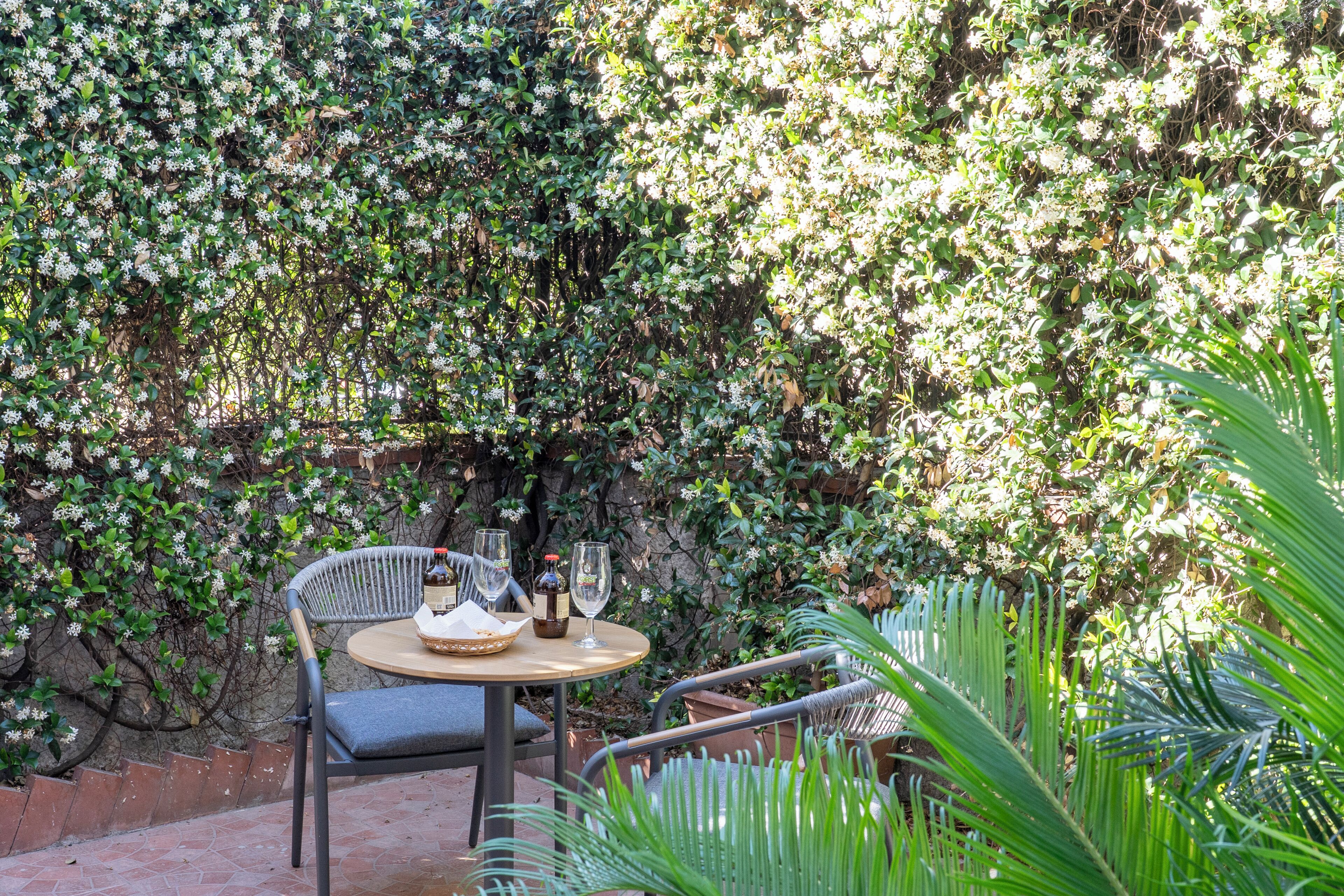 An outdoor seating area with a round table, two chairs, and a bottle of wine.