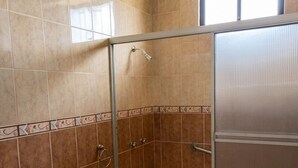 Un baño con ducha envuelta en vidrio, bañera y retrete.
