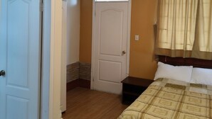 Un dormitorio con cama, puerta, ventana con cortinas y techo de madera.