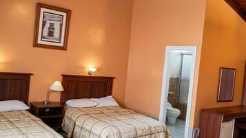 Quarto de hotel com duas camas, uma escrivaninha, um espelho e uma área de chuveiro.