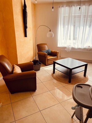 A living room with a brown leather sofa, a matching armchair, a small coffee table, and a floor lamp. - Spacious Holiday Home for 9 with Private Garden (Outreau)