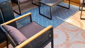 En udendørs terrasse med et træhegn, en sofa, et bord og stole.