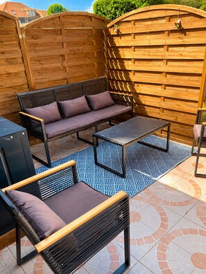 An outdoor patio with a wooden fence, a sofa, a table, and chairs. - Spacious Holiday Home for 9 with Private Garden (Outreau)