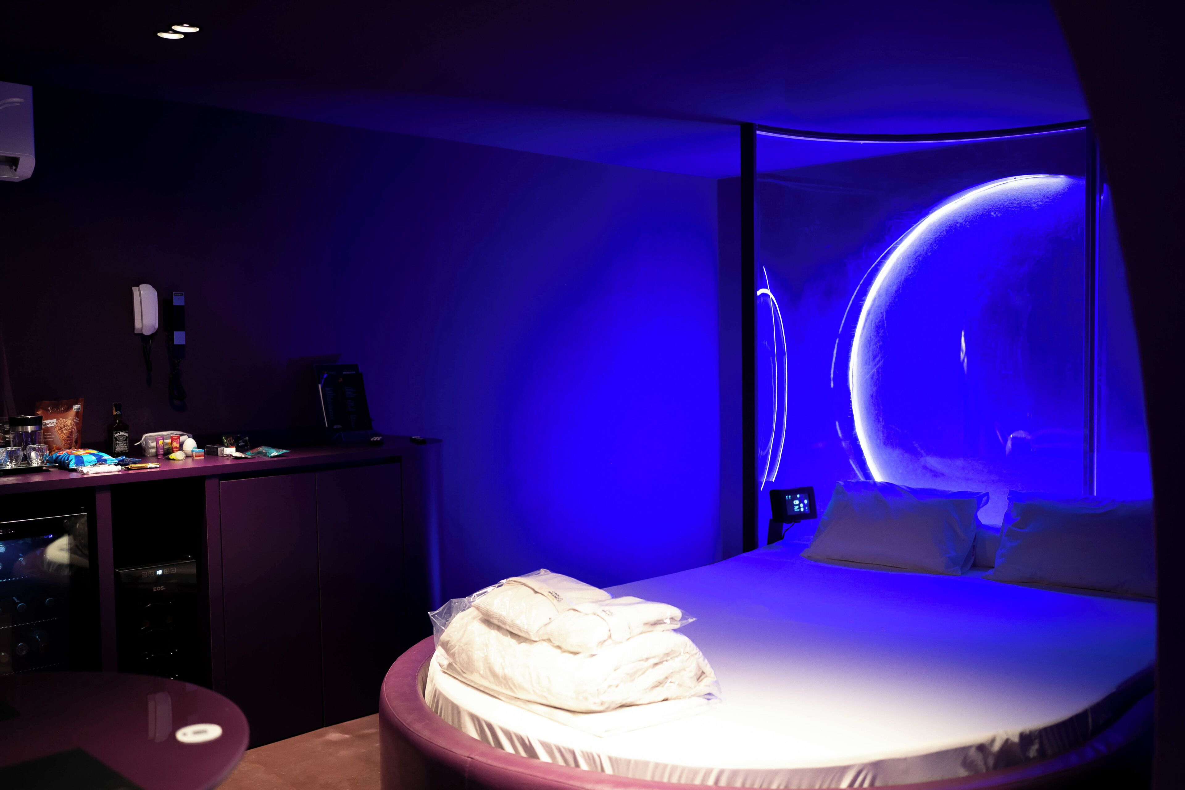 Ein Hotelzimmer mit einem Bett, einem Schreibtisch mit Computer und einem Wandfernseher.